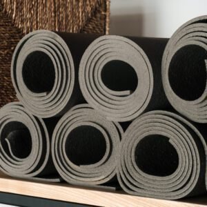 Gray yoga mats lying on a shelf, rolled up